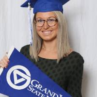 Upcoming graduate poses with the GV flag at GradFest